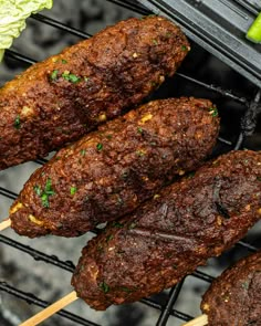 several skewered meats are being grilled on a bbq with lettuce