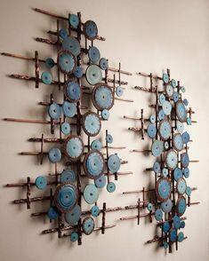 a wall sculpture made out of metal and blue buttons