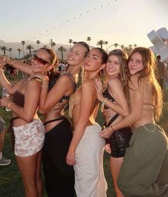 a group of young women standing next to each other on top of a grass covered field