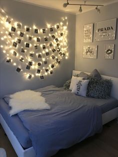 a bedroom with lights strung over the headboard and pictures on the wall above the bed