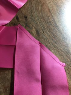 two pieces of pink fabric sitting on top of a wooden table