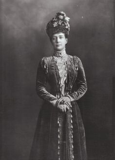 an old black and white photo of a woman wearing a dress with flowers in her hair