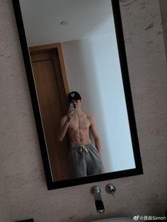 a shirtless man taking a selfie in front of a mirror with his cell phone