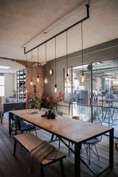 a wooden table sitting in the middle of a room with lots of lights hanging from it