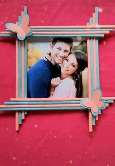 a photo frame hanging on the side of a red wall with an image of a man and woman