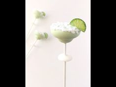 two margarita cocktails with lime and whipped cream on them sitting on top of each other