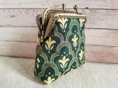 a green and gold purse sitting on top of a white table next to a wooden wall