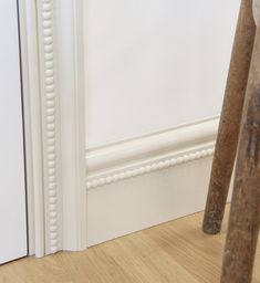 an old wooden chair sitting in front of a white wall next to a pair of scissors