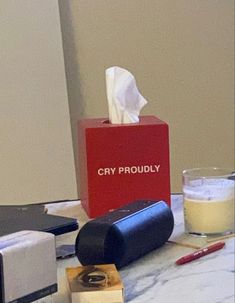 a red box sitting on top of a table next to a cup and tissue dispenser