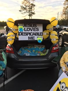 the back end of a car with balloons in the trunk that say jesus loves despicable me