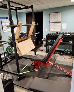 an empty gym room with equipment in the back and on the floor, including a bench