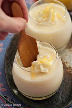 two desserts on a plate with a wooden spoon in one bowl and whipped cream in the other