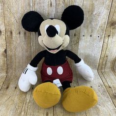 a mickey mouse stuffed animal sitting on top of a wooden floor