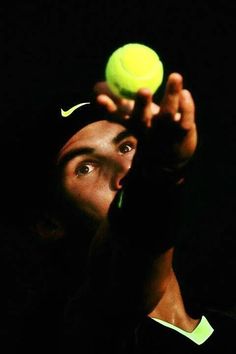 a man holding a tennis ball up to his face