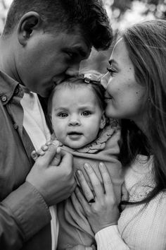 a man and woman holding a baby in their arms