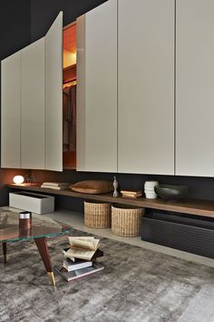 a living room with white cupboards and a glass table in front of the couch