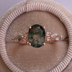 a ring with an oval shaped green stone surrounded by smaller stones