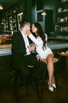 a man and woman sitting at a bar kissing