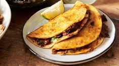 some tacos are sitting on a plate next to a bowl of rice and an apple