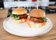 two chicken burgers sitting on top of a white plate with toothpicks sticking out of them