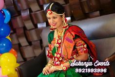 a woman sitting on top of a couch wearing a green and red sari with balloons in the background