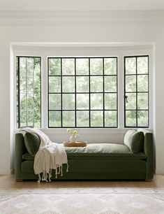 a green couch sitting in front of two windows