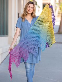 a woman is walking down the street with her colorful shawl