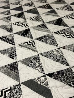 a black and white quilt is laying on top of a tablecloth with geometric designs