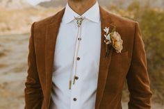 a man wearing a brown suit and flower boutonniere