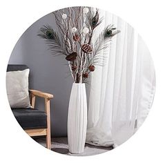 a white vase filled with lots of flowers next to a window covered in sheer curtains