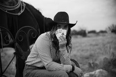 black and white photograph of a woman sitting on a bench with a horse in the background