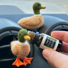 someone is holding an essential oil in their hand and there are two ducks on the dashboard