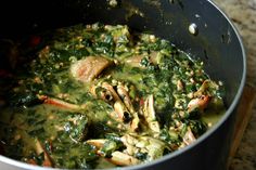 a pot filled with greens and meat on top of a table