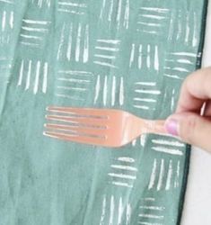 a person is holding a fork in their left hand, on top of a green napkin