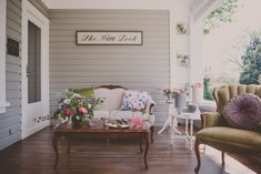 a living room filled with furniture and flowers on top of a hard wood floored floor