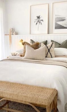 a bed with white linens and pillows in a bedroom next to two pictures on the wall