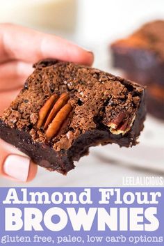 someone holding up a piece of brownie with pecans on top and almonds in the middle