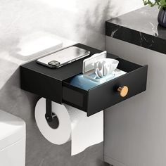 a black and white tray with tissue, toilet paper and cell phone on it next to a mirror