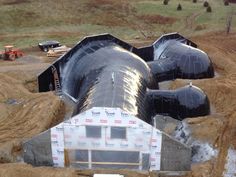 a large pipe laying on top of a dirt field next to a building under construction