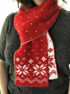 a woman wearing a red knitted scarf with white snowflakes and hearts on it