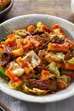 a bowl filled with stir fried vegetables next to chopsticks