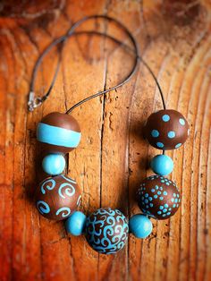 a necklace made out of chocolate and blue beads on a wooden surface with a leather cord