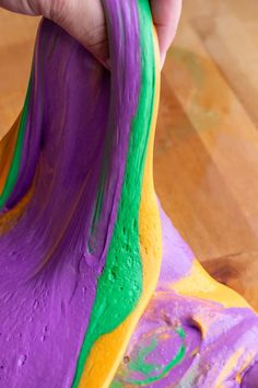 someone is painting the bottom part of a banana with purple, green and yellow paint