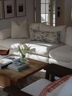 a living room with white couches and flowers in a vase on the coffee table