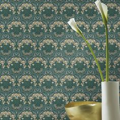 a vase with two flowers in it next to a wallpapered background that looks like an ornament