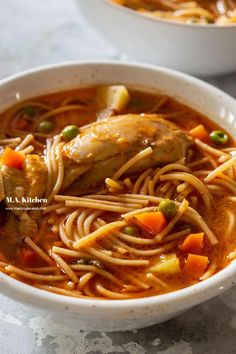 two white bowls filled with chicken noodle soup