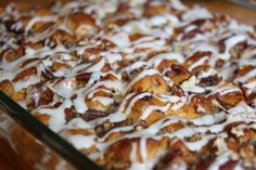 a glass dish filled with cinnamon rolls covered in icing