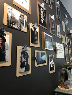 a wall covered in pictures and magnets next to a vase with flowers on it