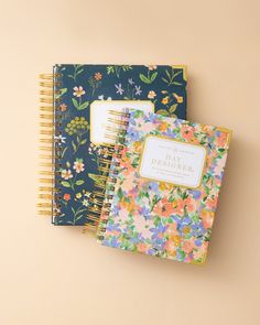 two notebooks sitting next to each other on top of a table with floral designs