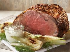 a large piece of meat sitting on top of a white plate next to some vegetables